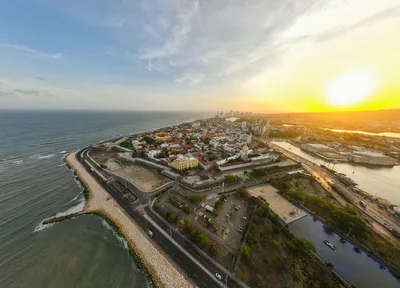 Stunning aerial view of a coastal cityscape with the sun rising over the horizon.