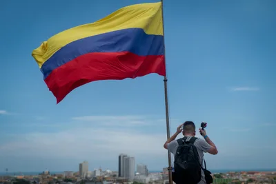 Back view of a man photographing the Colombian flag in Cartagena, Colombia.