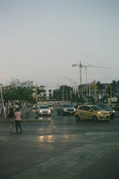Busy street scene in Cartagena with cars and pedestrians during evening time.