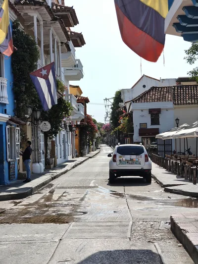 Charming street scene in Cartagena, Colombia, showcasing vibrant architecture and flags.