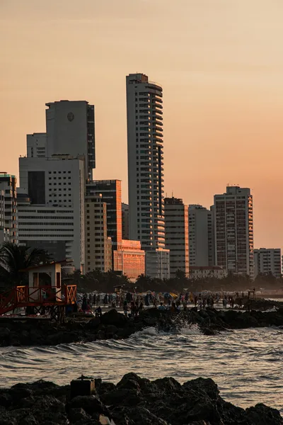 Stunning view of Cartagena's skyline during sunset with ocean waves in the foreground.