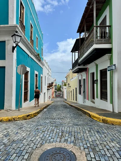 Charming view of a vibrant street in Old San Juan, featuring colorful buildings and a cobblestone path.