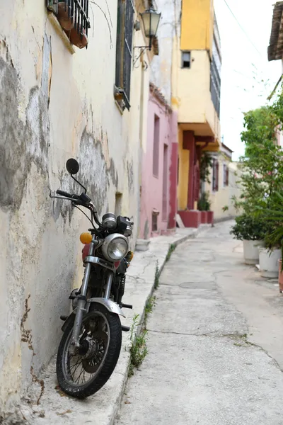 A vintage motorbike parked in a narrow, colorful urban alley with rustic walls.